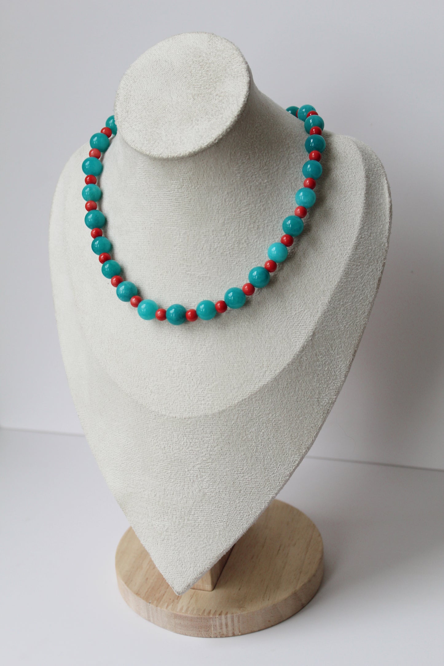 Turquoise and coral-colored beaded necklace displayed on a jewelry bust.
