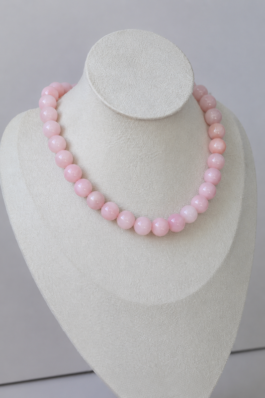Handcrafted blush pink acrylic beaded necklace displayed on a jewelry bust.