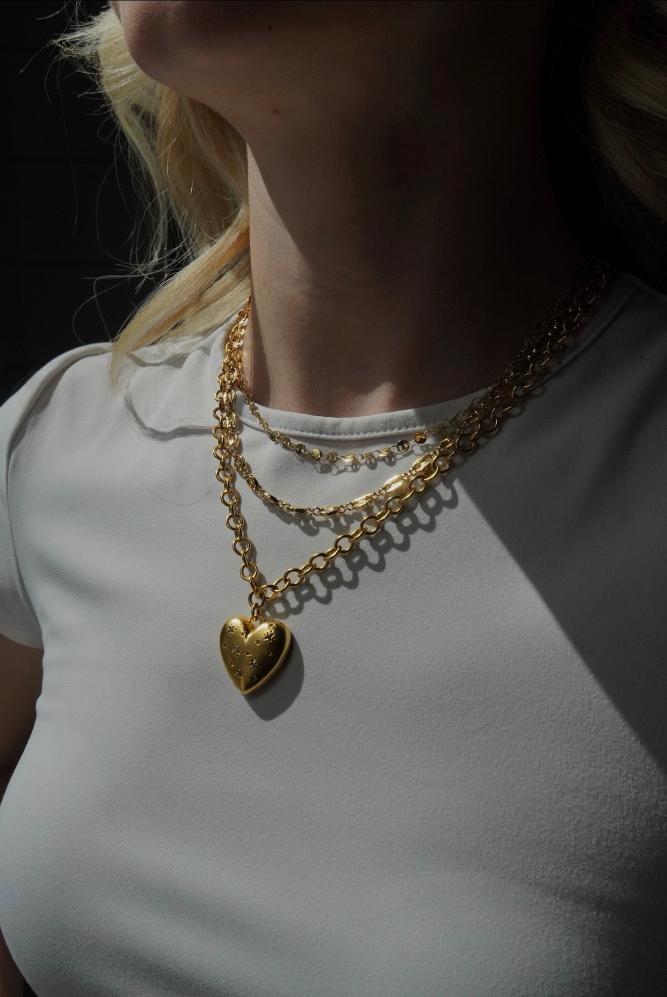 Woman wearing the Close to Heart Necklace layered with gold jewelry