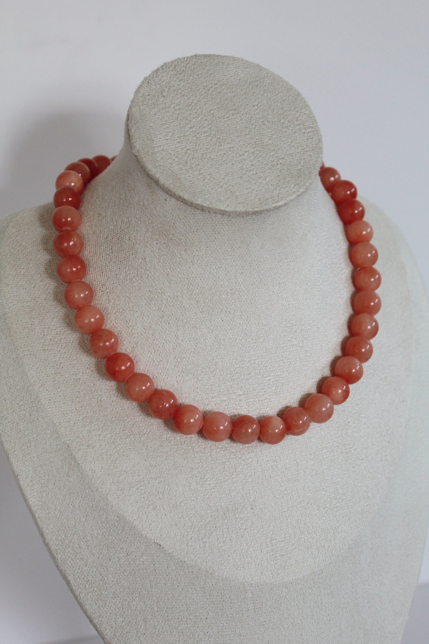 Handcrafted coral pink acrylic beaded necklace displayed on a jewelry bust.