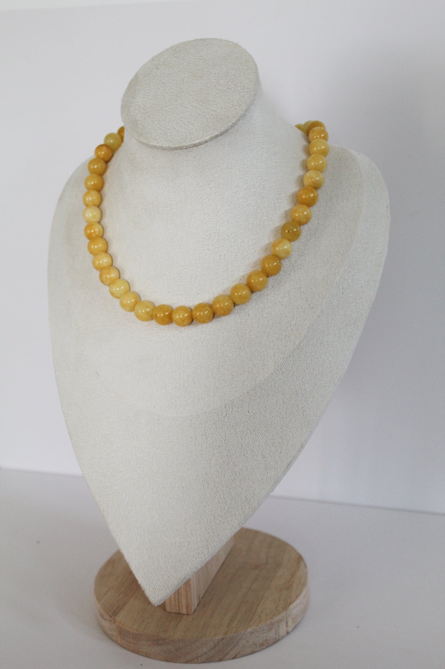 Handcrafted butter-yellow acrylic beaded necklace displayed on a jewelry bust.
