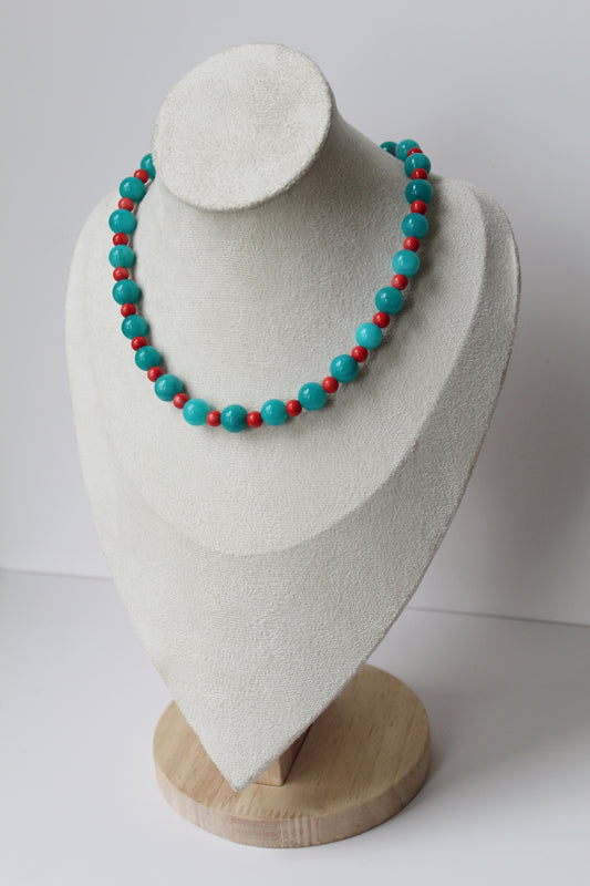Turquoise and coral-colored beaded necklace displayed on a jewelry bust.