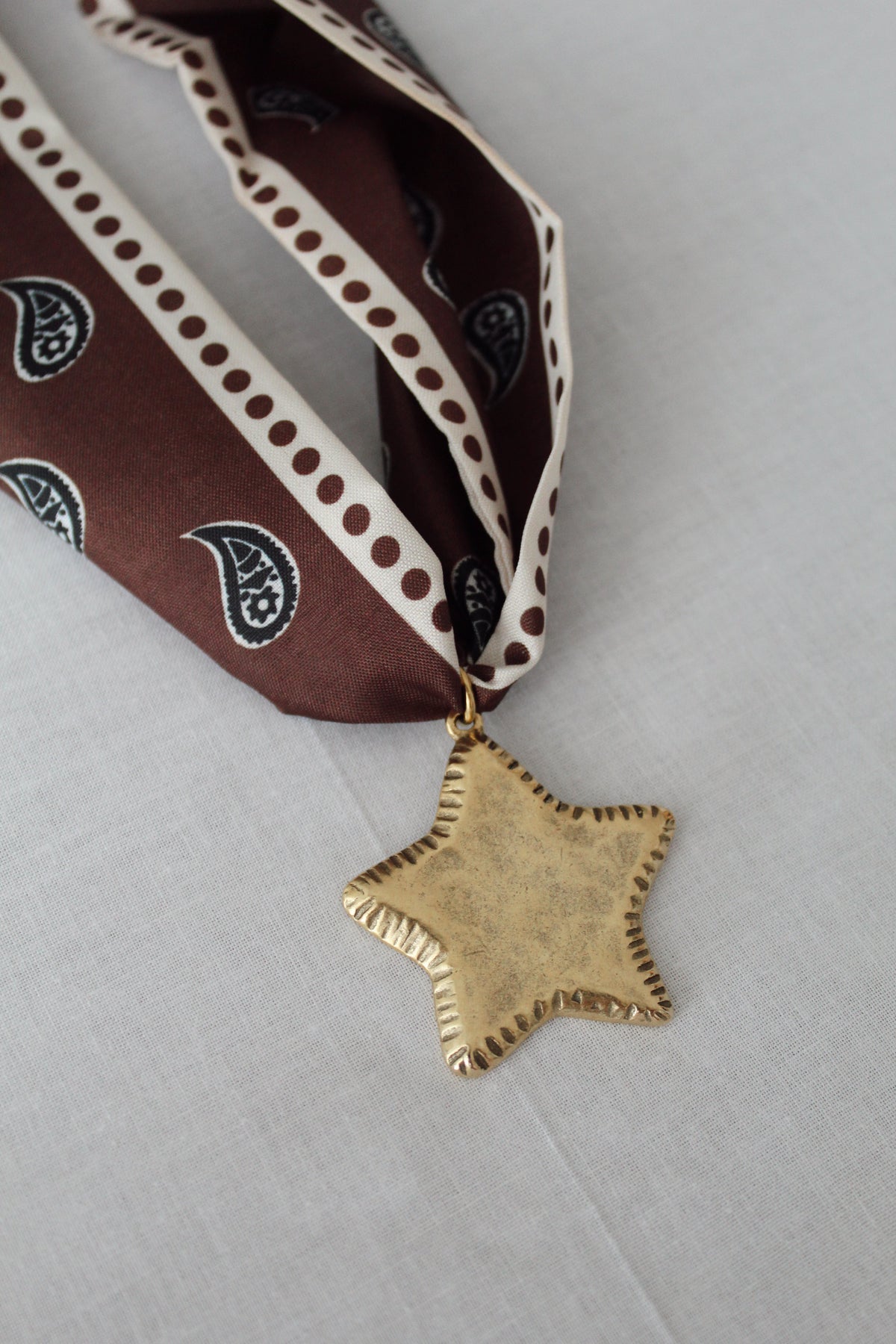 Oversized gold star pendant on chocolate brown paisley scarf necklace
