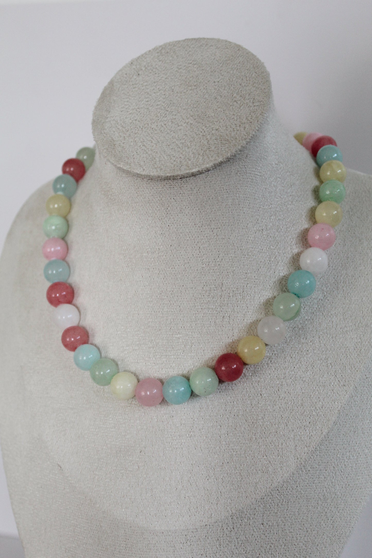 Handcrafted pastel acrylic beaded necklace featuring pink, mint, aqua, butter yellow, cream, and berry-colored beads displayed on a jewelry bust.