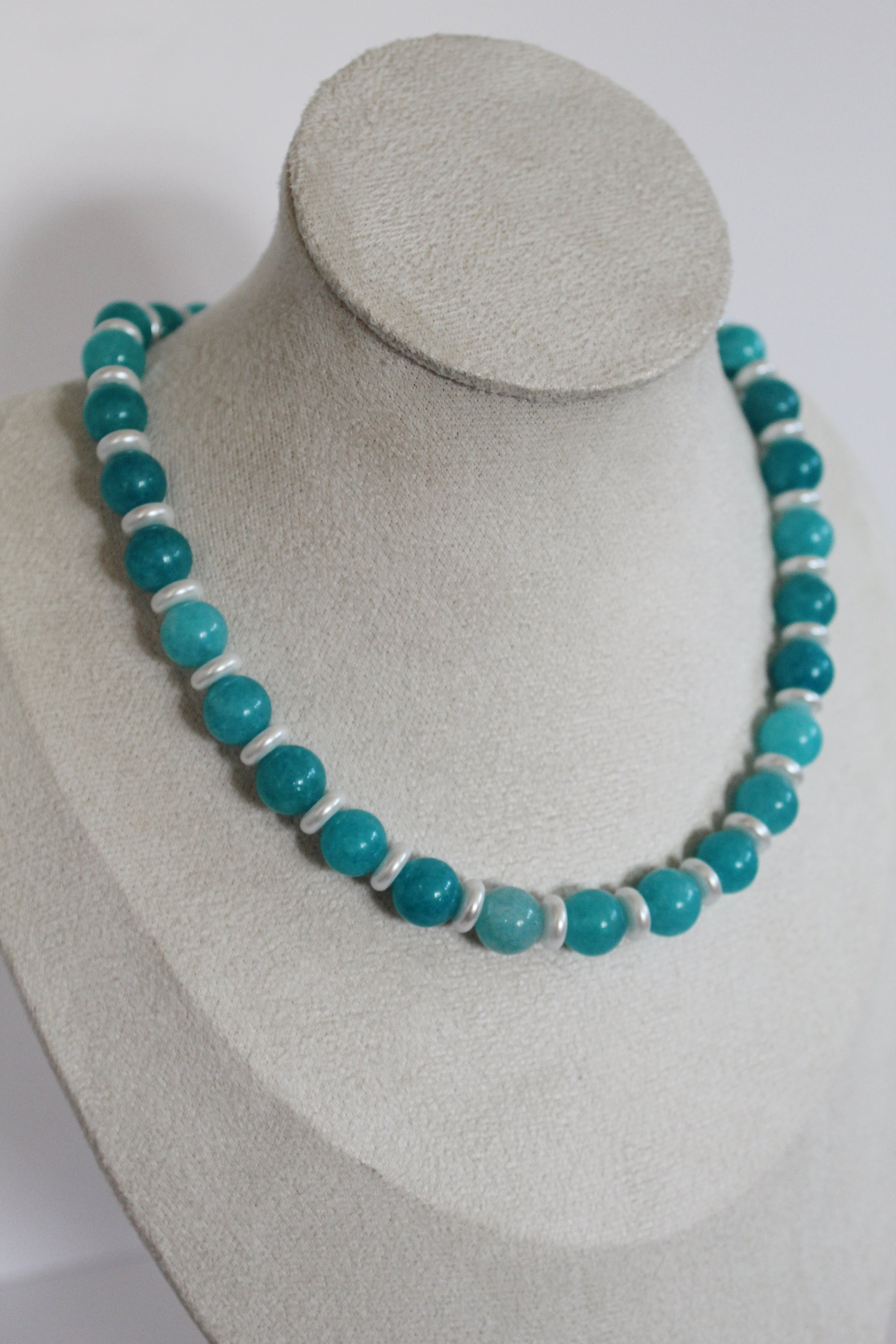 Handcrafted aqua beaded necklace with pearl accents displayed on a jewelry bust.