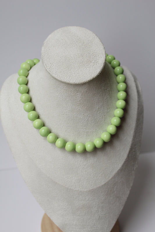 Pistachio green beaded necklace displayed on a jewelry bust.