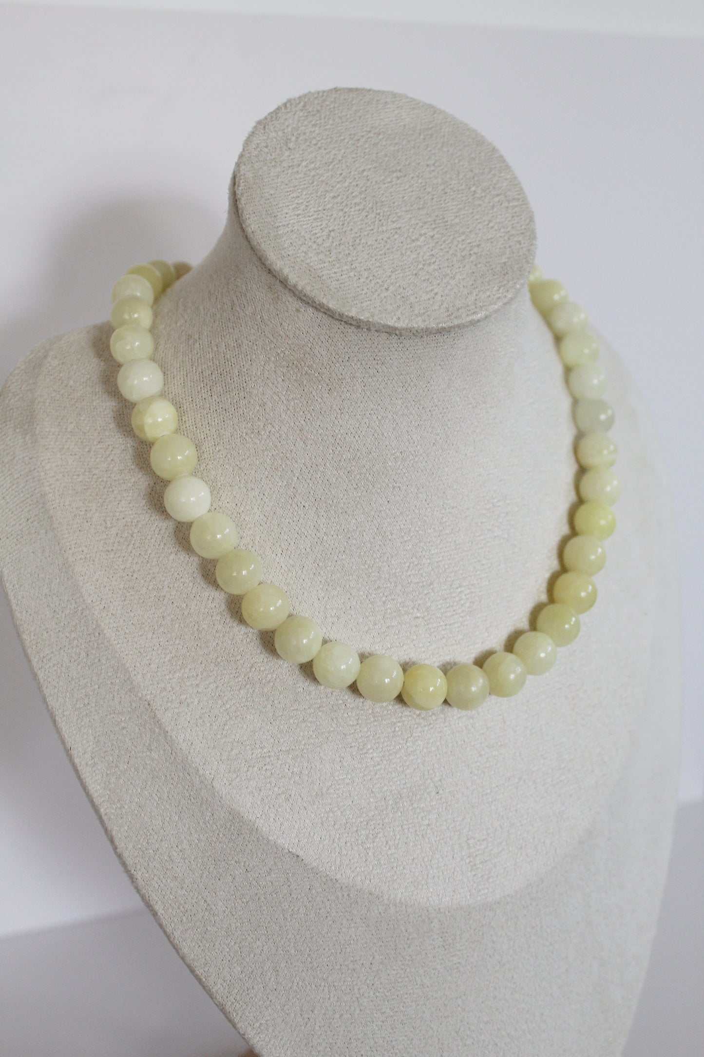 Handcrafted butter yellow acrylic beaded necklace displayed on a jewelry bust.
