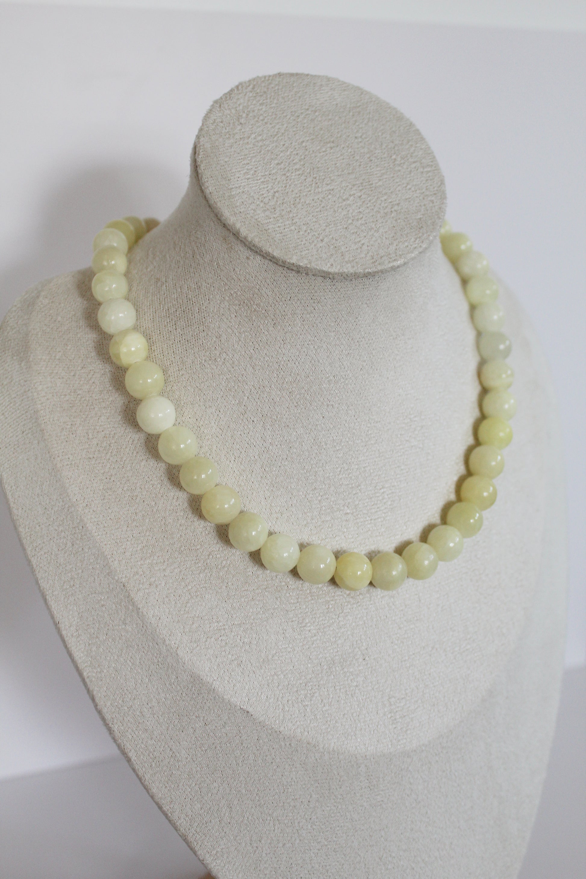 Handcrafted butter yellow acrylic beaded necklace displayed on a jewelry bust.