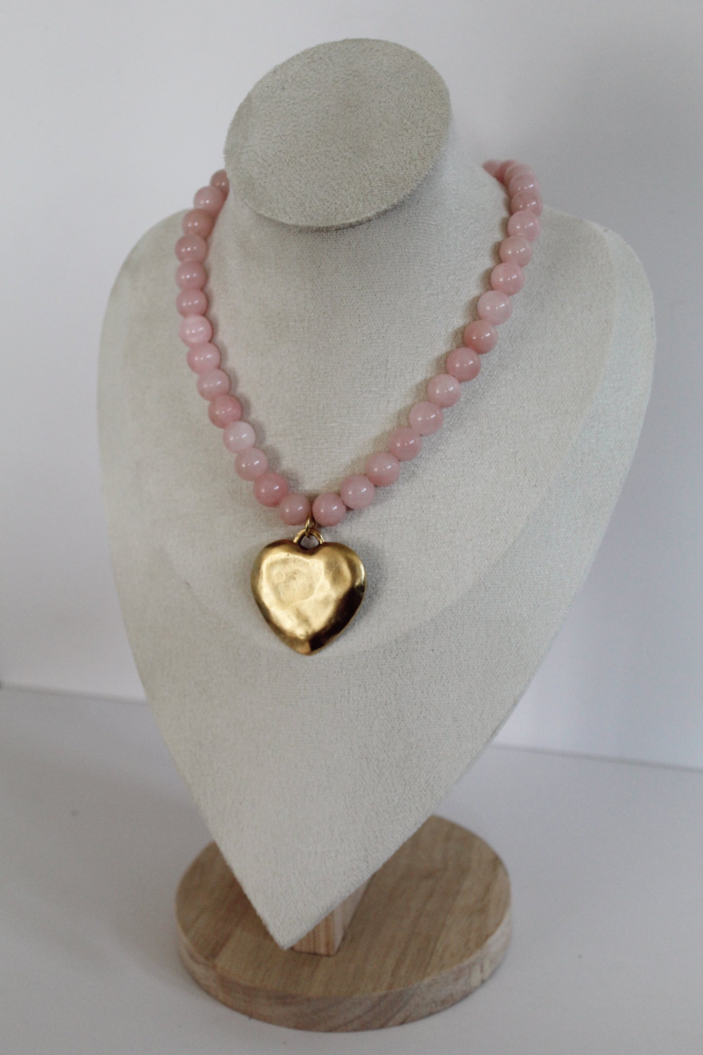 Handcrafted pink acrylic beaded necklace with a gold stainless steel heart charm displayed on a jewelry bust.