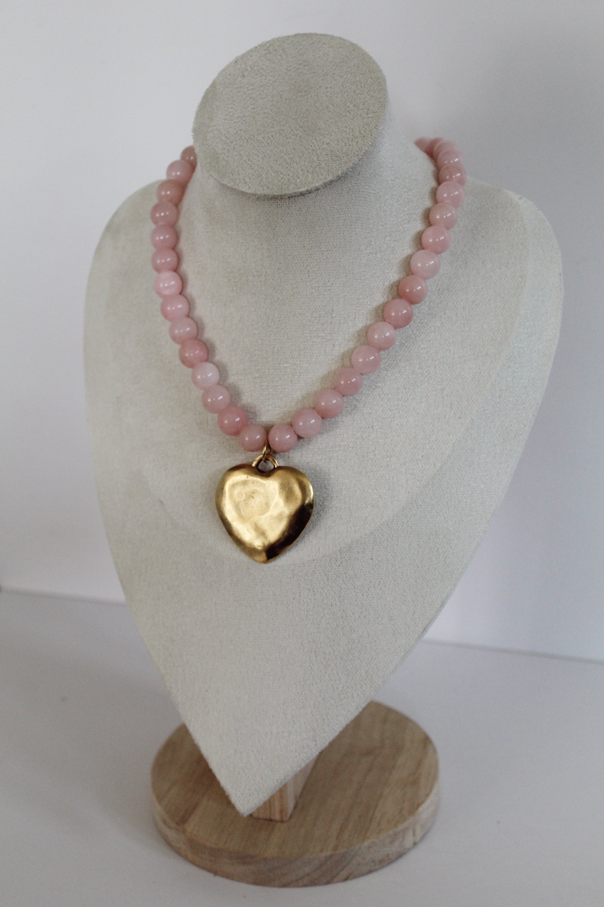 Handcrafted pink acrylic beaded necklace with a gold stainless steel heart charm displayed on a jewelry bust.