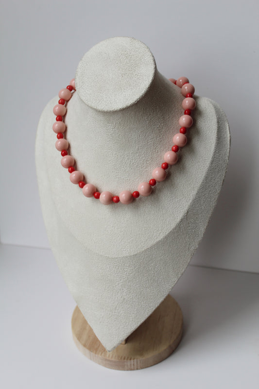 Blush pink and strawberry red beaded necklace displayed on a jewelry bust.