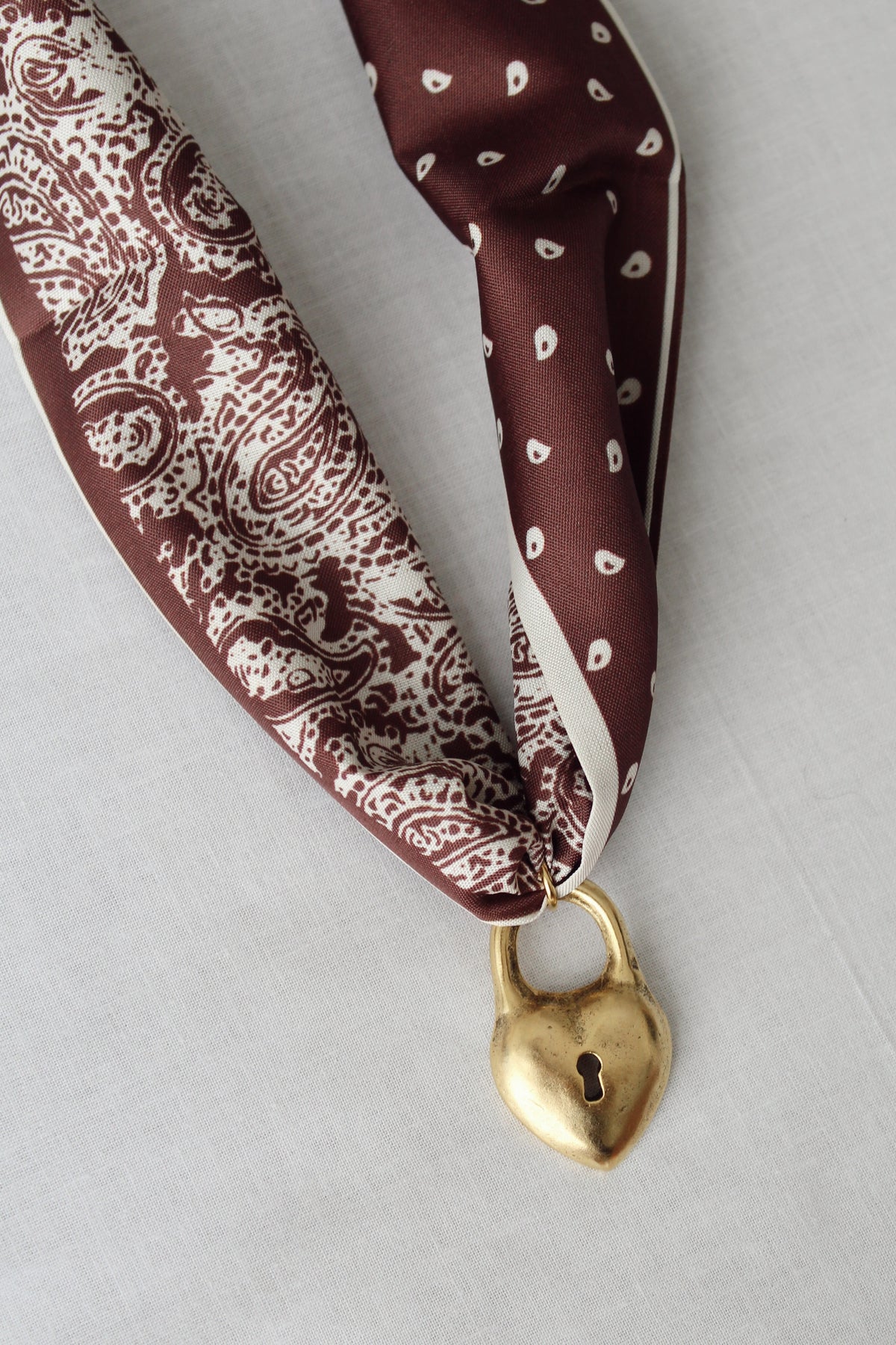 Vintage-inspired gold heart lock pendant on brown paisley scarf necklace