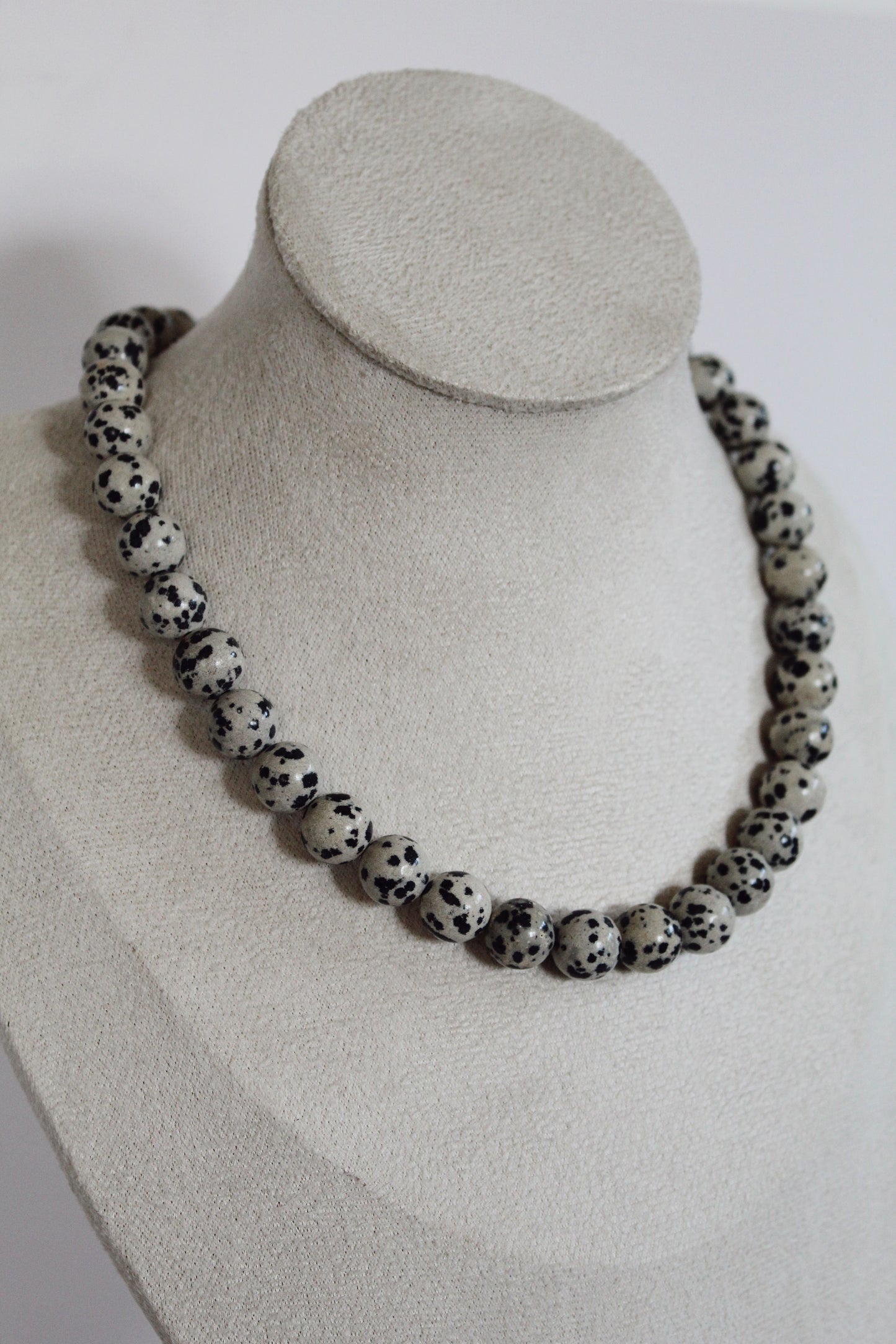 Handcrafted black and white speckled acrylic beaded necklace displayed on a jewelry bust.