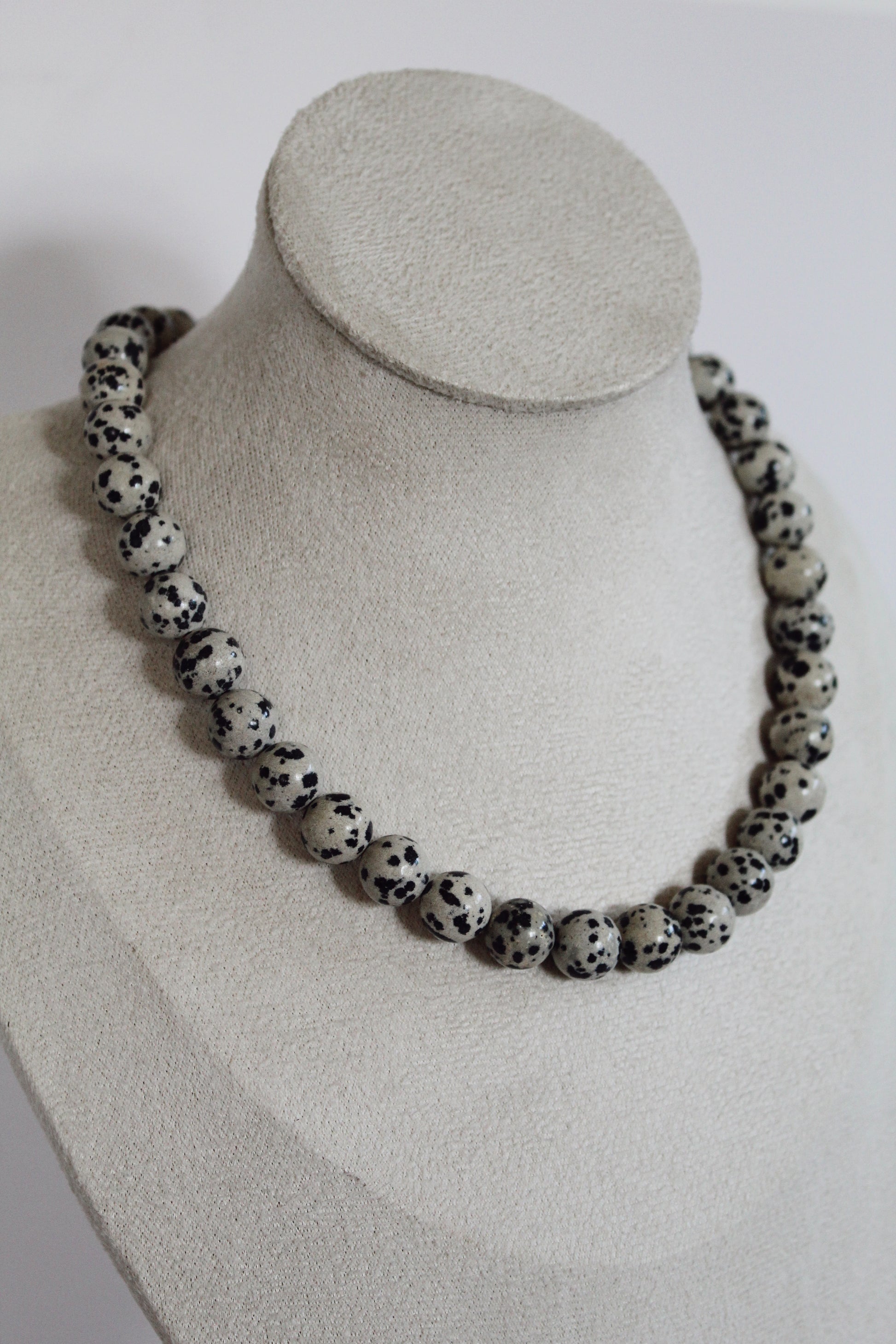 Handcrafted black and white speckled acrylic beaded necklace displayed on a jewelry bust.