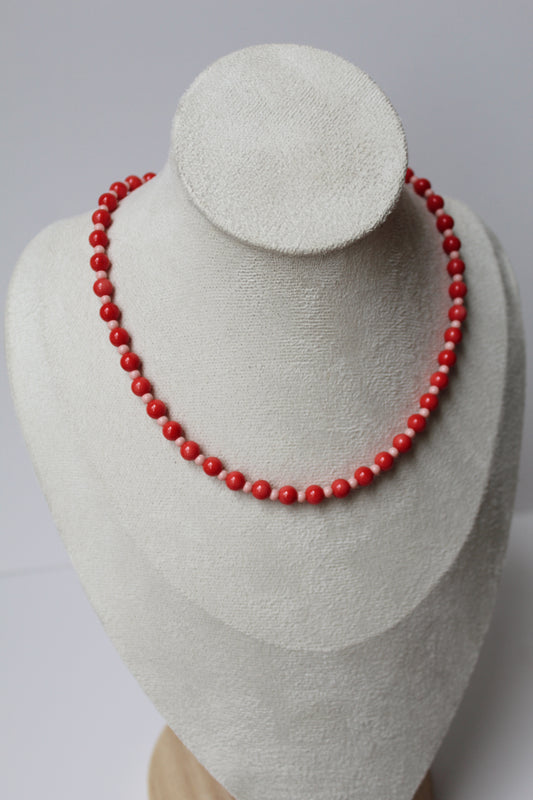 Red and blush pink beaded necklace displayed on a jewelry bust.