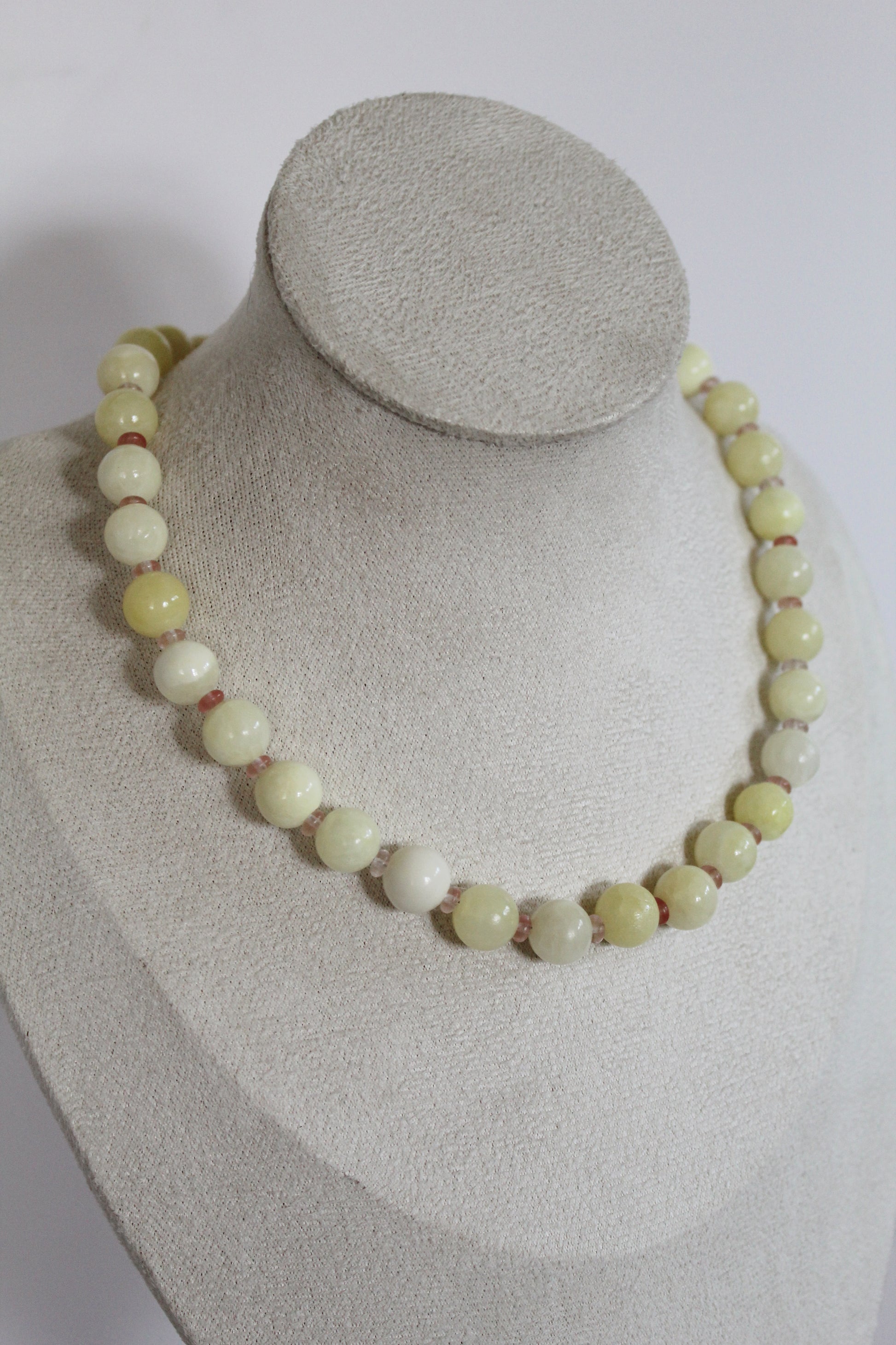 Handcrafted pastel yellow acrylic beaded necklace with blush pink spacer beads displayed on a jewelry bust.